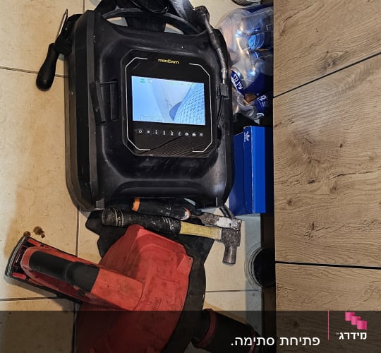 כלי עבודה של אינסטלטור על רצפה, כולל מצלמה וצינור
